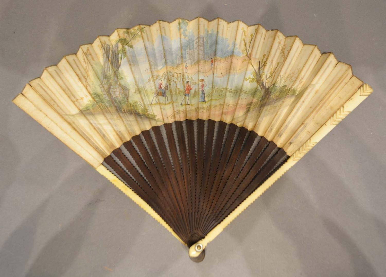 An Early 18th Century German Fan, hand painted with figures within a landscape with shaped wooden