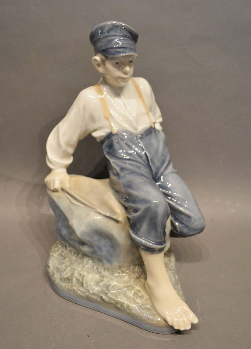 A Royal Copenhagen Porcelain Large Model of a Fisherboy Seated on a Rock, numbered 1659, 30cm tall