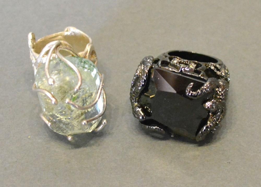 A Large Black Dress Ring, together with another similar dress ring