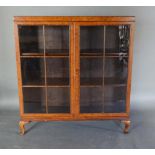 An Early 20th Century Burr Walnut Display Cabinet with two bar glazed doors enclosing shelves,