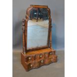 A 19th century Queen Anne Style Walnut Dressing Mirror, the shaped mirror above four drawers with