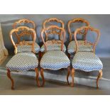 A Set of Six Victorian Walnut Balloon Back Dining Chairs, the carved pierced rail back above a stuff