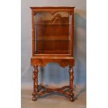 A Queen Anne Style Walnut Display Cabinet, the glazed top with side opening door above a shaped