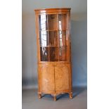A Queen Anne Style Burr Walnut Bow-fronted Standing Corner Cabinet by Maple, the moulded cornice