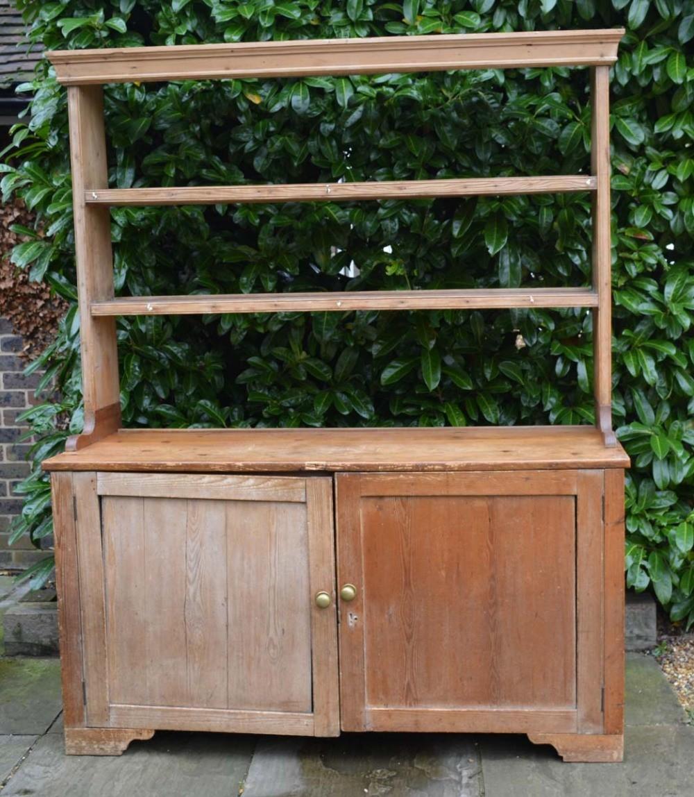 A 19th Century Pine Dresser, the open shelf back above two panel doors with brass knob handles