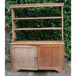 A 19th Century Pine Dresser, the open shelf back above two panel doors with brass knob handles