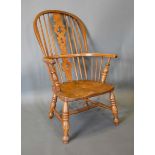An Early 19th Century Elm Windsor Armchair with a pierced splat and spindle back above a shaped seat