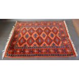 A Turkish Woollen Konya Rug with an allover design upon a terracotta and blue ground within multiple
