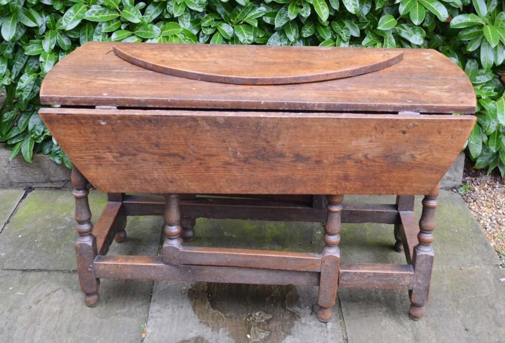 A George III Oak Oval Gateleg Dining Table with turned legs and stretchers