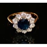 An 18 Carat Gold Sapphire and Diamond Cluster Ring with a central sapphire surrounded by diamonds,