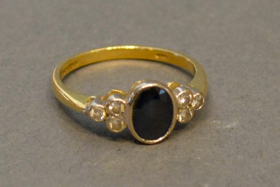 An 18 Carat Yellow Gold Sapphire and Diamond Ring, the oval central sapphire flanked by a cluster of