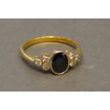 An 18 Carat Yellow Gold Sapphire and Diamond Ring, the oval central sapphire flanked by a cluster of