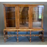 An Early 20th Century Queen Anne Style Walnut Bookcase, the moulded top above three glazed doors