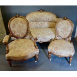 A Victorian Walnut Drawing Room Suite comprising a sofa with a carved back above a stuff over seat