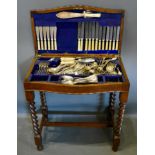 An Edwardian Oak Serpentine Fronted Canteen Cabinet raised upon barley twist legs containing mixed