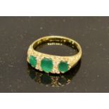 An 18 Carat Gold Emerald and Diamond Ring set with three emeralds interspaced with small diamonds,