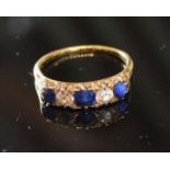 A Yellow Metal Ring set three sapphires and two diamonds within a pierced setting