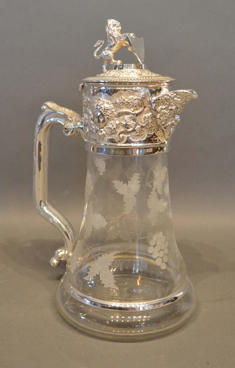 A Glass and Silver Plated Claret Jug with lion surmount and engraved with grapevines, 27cm tall