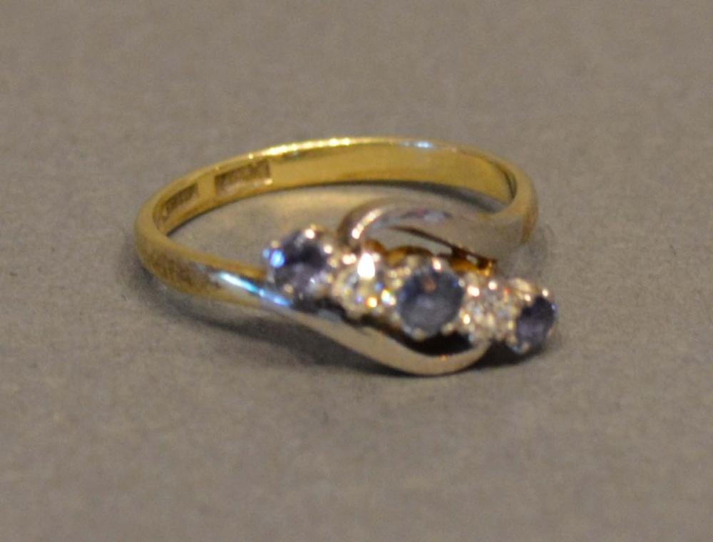 An 18 Carat Gold Sapphire and Diamond Crossover Ring set with three sapphires and two diamonds