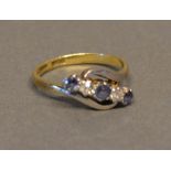 An 18 Carat Gold Sapphire and Diamond Crossover Ring set with three sapphires and two diamonds
