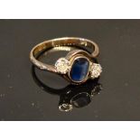 A 9 Carat Crossover Ring set with an oval sapphire flanked by diamonds, 2.5 grammes