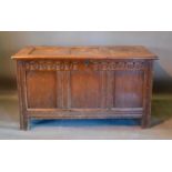 An 18th Century Oak Coffer, the hinged top above a three panel front flanked by stiles, 123cm