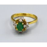 A 18ct Yellow Gold Emerald and Diamond Cluster Ring set with an oval central emerald surrounded by