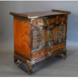 A Korean Table Cabinet with an arrangement of doors and drawers raised upon shaped supports, 67cm