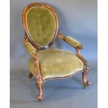 A Victorian Walnut Drawing Room Armchair with carved oval back and button upholstery, above an