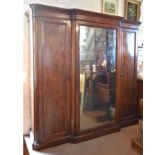 A William IV Mahogany Triple Wardrobe with shaped stepped cornice above a large central mirrored