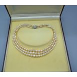 A Graduated Cultured Pearl Three Strand Choker with white metal clasp set with central pearl