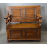 An Early 20th Century Oak Monk's Bench, the hinged top above a double linenfold back above a similar