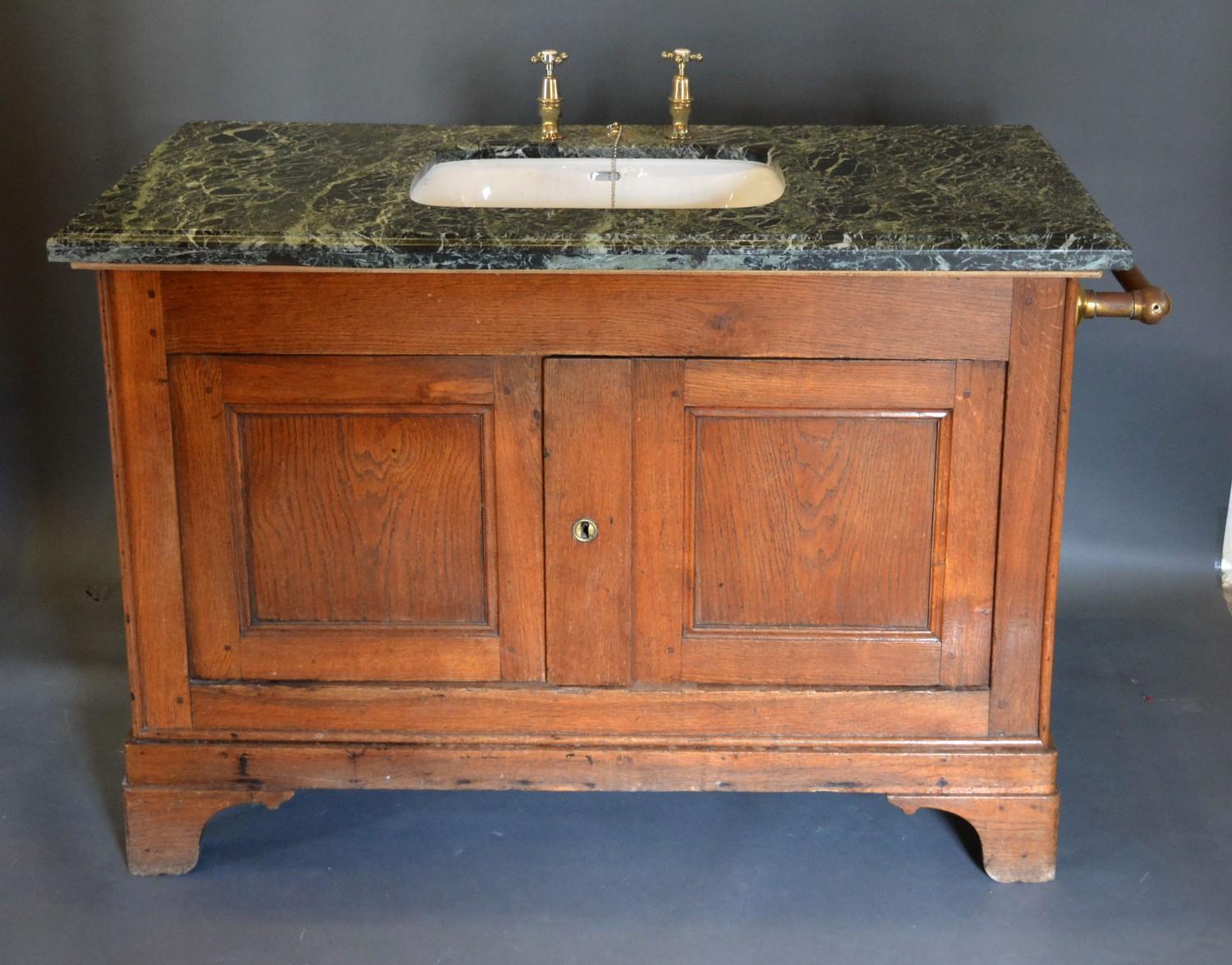 A Large Sink with a variegated marble top upon a 19th century oak base with two panel doors raised