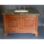 A Large Sink with a variegated marble top upon a 19th century oak base with two panel doors raised