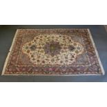 An Isfahan Silk Rug with a central medallion within an allover design upon a cream ground within