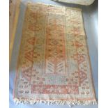 A Turkish Woollen Rug with an all over design on a pale cream blue and terracotta ground within