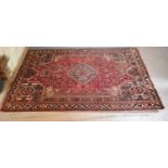 A Northwest Persian Woollen Rug with a central medallion within an all over design upon a red,