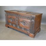 An Oak Coffer with Moulded Hinged Top with three panels above a carved two panel front raised upon