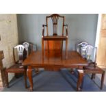 An Early 20th Century Walnut Wind Out Extending Dining Table with single extra leaf, together with a