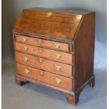 A George III Oak Bureau with fall front enclosing a fitted interior with four drawers with brass