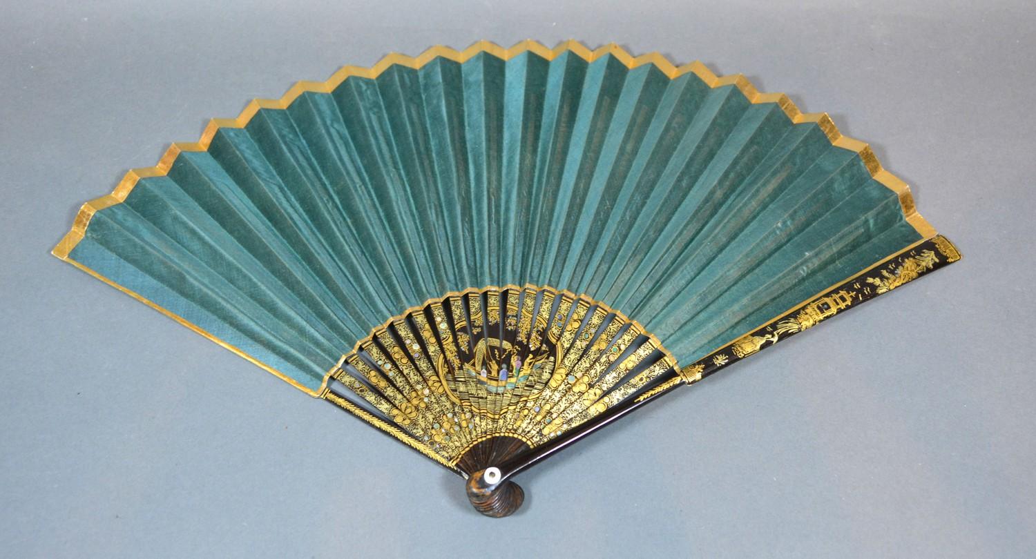 A Regency Period Fan with plain green silk leaf within a gilt border, lacquered sticks and guards,