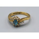 A 9ct Yellow Gold Diamond Set Ring with Central Blue Stone surround by diamonds in a crossover