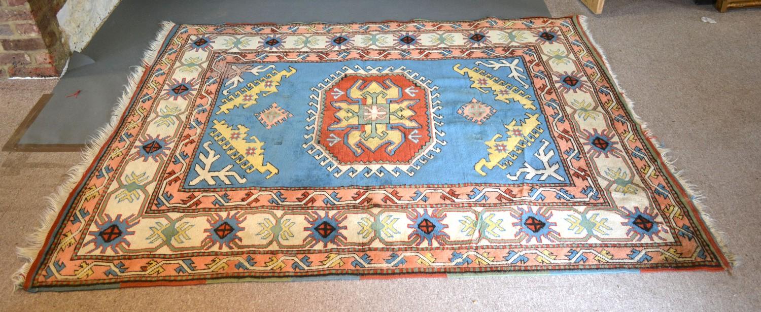 A Kazak Woollen Rug with a central medallion within an all-over design upon a terracotta, blue and