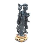 A Chinese Dark Blue and Goldstone Figure in the form of a girl in period costume on hardwood stand