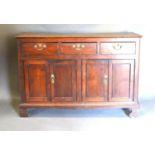 A George III Oak Dresser Base, the plank top above three drawers and four cupboard doors with