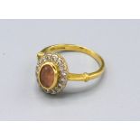 An 18ct. Gold Citrine and Diamond Cluster Ring with a central oval citrine surrounded by diamonds,