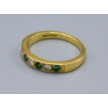 An 18ct. Gold Emerald and Diamond Band Ring set four emeralds and three diamonds, ring size N, 3.6