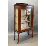 An Edwardian Mahogany Display Cabinet with an astragal glazed door enclosing shelves raised upon