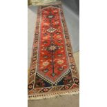 A North West Persian Woollen Runner with an all over design upon a red, blue and terracotta ground