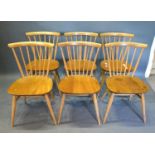 A Set of Six Ercol Blonde Ash Dining Chairs each with a stick back above a panel seat raised upon